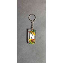 Miina Aksesuar Kurutulmuş Çiçeklerle Süslenmiş Epoksi Malzemeden Üretilmiş Kişiselleştirilmiş Bir Harf Anahtarlıktır.