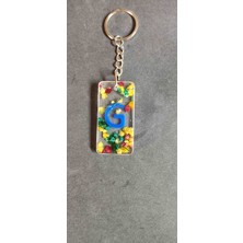 Miina Aksesuar Kurutulmuş Çiçeklerle Süslenmiş Epoksi Malzemeden Üretilmiş Kişiselleştirilmiş Bir Harf Anahtarlıktır.