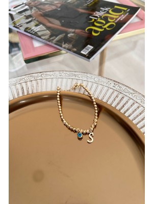 Mediterian S harfli nazar sallantılı dorika bileklik, altın renkli zarif takı modeli.