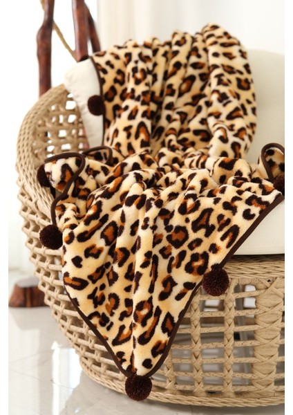 Leopar desenli peluş TV battaniyesi, ponpon detaylarıyla şık ve sıcak kullanım sağlar.