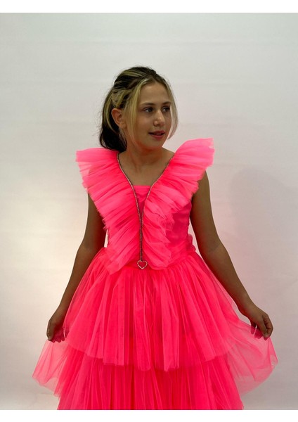 Kız Çocuk Abiye Neon Pembe Uzun Kat Etekli Kolları Fırfırlı Yakası Taş Detaylı Kalp Tokalı Abiye Elbise 10-14 Yaş modelleri