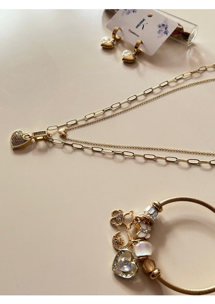 Gold Renk Paslanmaz Çelik Inci Boncuk Zincirli Kalp Sallantılı Kolye, Beyaz Zirkon Taşlı Kalp Sallantılı Çivi Küpe ve Kalp Detaylı Charm Bileklik 3’lü Set fiyatları