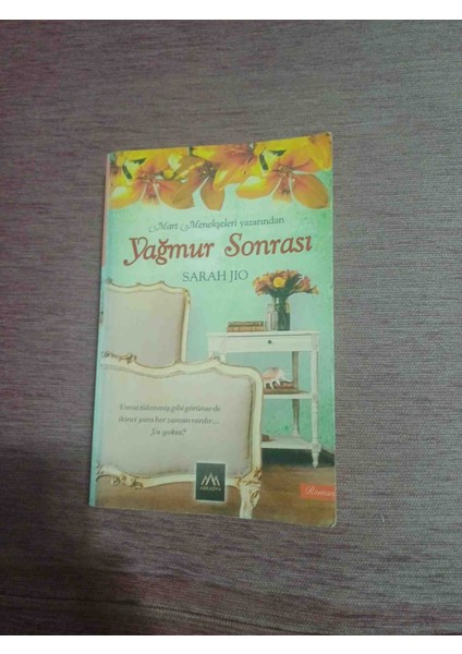 Sarah Jio'nun Yağmur Sonrası Romanı, Sandalye, Masa ve Çiçeklerin Yer Aldığı Sakin Bir Kapak Tasarımına Sahip. Yağmur Sonrası Aşk ve Iyileşme Temalarını Işler. Yagmur Sonrasi Sarah Jio 2015 Basim