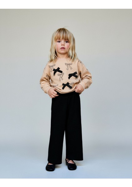 Kız Çocuk Pamuklu Bej Fiyonk Desenli Sweatshirt ve Siyah Pantolon Takım – Şık ve Rahat Kombin