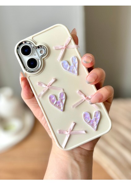 IPHONE 16 3D Kalp ve Fiyonk Dekorlu Ekru Renk Kılıf